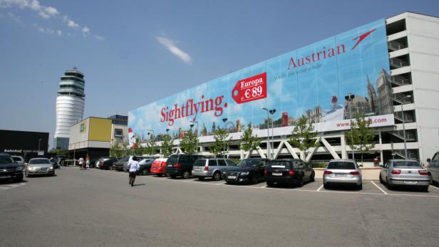 Ein Parkplatz vor dem Flughafen Wien mit einem großen „Austrian Sightflying“-Werbeplakat.