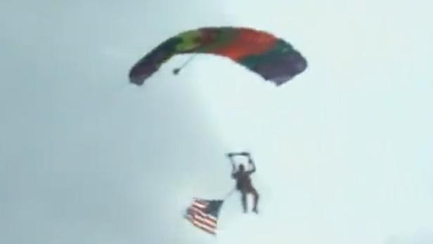 Ein Fallschirmspringer schwebt mit einer amerikanischen Flagge am Himmel.
