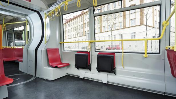 Innenansicht eines modernen Busses mit roten Sitzen und Haltestangen.