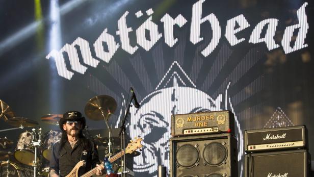 Lemmy Kilmister von Motörhead tritt auf der Bühne vor dem Bandlogo auf.