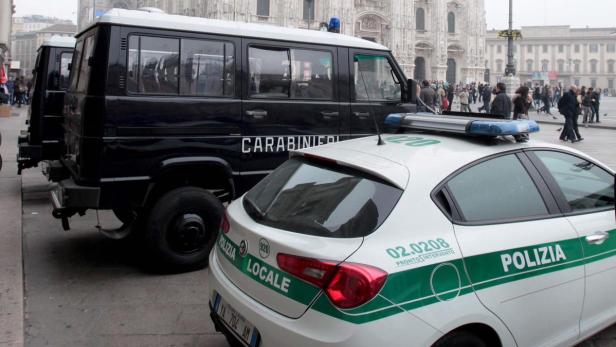 Ein Polizeiauto und ein Carabinieri-Fahrzeug stehen vor einem Gebäude in Mailand.
