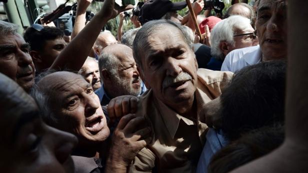 Eine Menschenmenge drängt sich um einen Mann mit Schnurrbart.