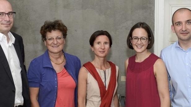 Fünf Personen posieren für ein Gruppenfoto vor einer grauen Wand.