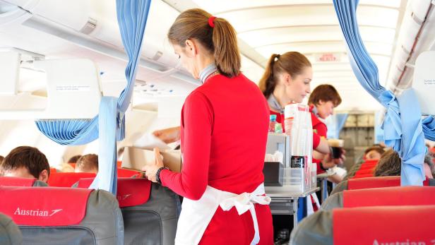 Eine Flugbegleiterin von Austrian Airlines serviert Essen an Bord eines Flugzeugs.