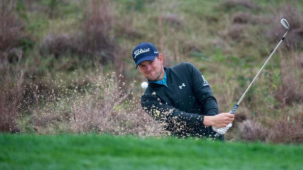 Ein Golfspieler schlägt einen Ball aus einem Sandbunker.