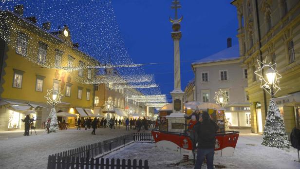 Ein verschneiter Platz in einer Stadt, geschmückt mit Lichtern zur Weihnachtszeit.