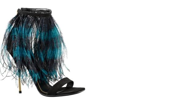 Ein schwarzer High-Heel-Sandalen mit blau-schwarzen Federn verziert.