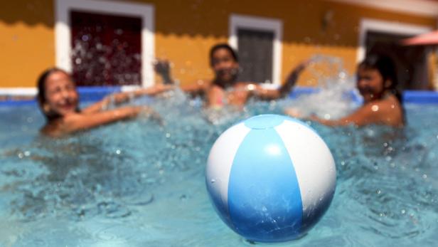 epa03776933 With temperatures reaching 40 degrees Celsius youngsters play with a ball inside their swimming pool, Elvas, southern Portugal, 05 July 2013. EPA/NUNO VEIGA