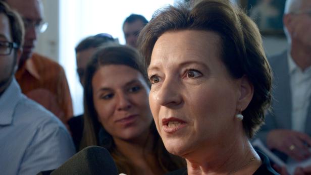 Eine Frau spricht in ein Mikrofon, umgeben von anderen Personen.