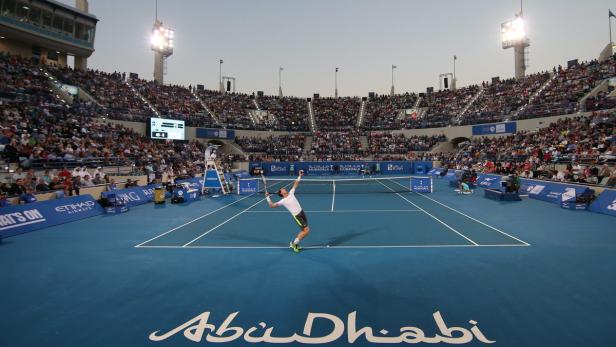 Ein Tennisspieler serviert bei einem Spiel in Abu Dhabi vor vollen Zuschauerrängen.