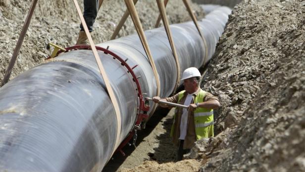 Ein Arbeiter montiert eine große Pipeline in einem Graben.