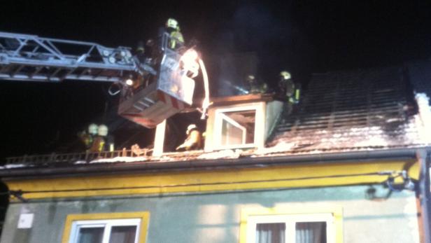 Feuerwehrleute bekämpfen einen Brand auf dem Dach eines Hauses.