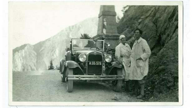 Alban und Helene Berg in weißen Mänteln vor dem Auto