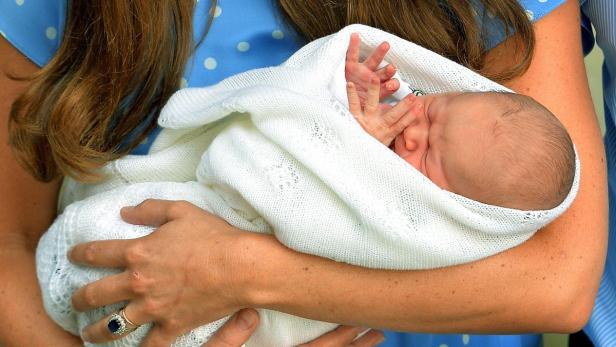 Eine Frau hält ein in eine weiße Decke gewickeltes Baby im Arm.