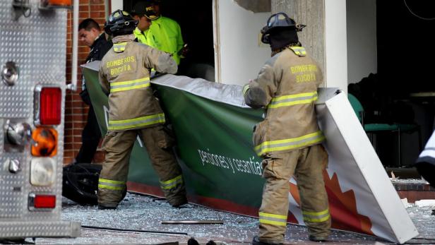 Zwei Feuerwehrleute aus Bogotá räumen Trümmer nach einer Explosion weg.