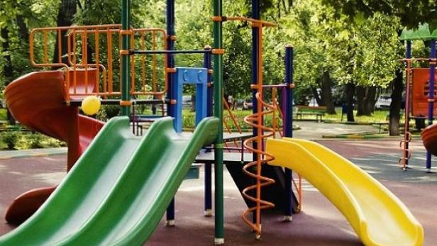 Ein farbenfroher Spielplatz mit Rutschen und Klettergerüsten in einem Park.