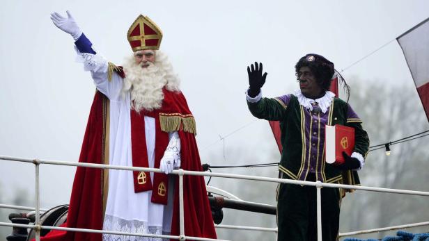Sinterklaas und ein Helfer winken von einem Schiff.