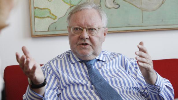 Ein Mann mit Brille und gestreiftem Hemd gestikuliert während eines Gesprächs.