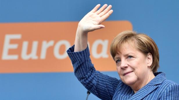 Angela Merkel winkt vor einem orangefarbenen Banner mit der Aufschrift „Europa“.
