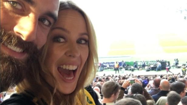 Kylie Minogue macht ein Selfie mit einem Mann bei einer Sportveranstaltung.