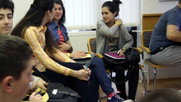 Eine Gruppe junger Leute sitzt im Kreis und diskutiert.