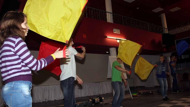 Eine Gruppe von Menschen schwingt farbige Flaggen in einem Raum.