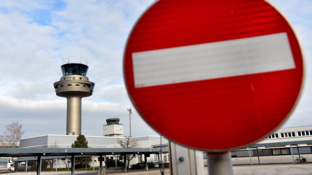 Ein rotes Verkehrsschild mit einem Flughafen-Kontrollturm im Hintergrund.