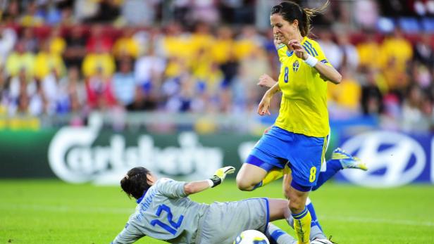 Eine schwedische Fußballspielerin dribbelt den Ball, während eine Torhüterin versucht, ihn abzuwehren.