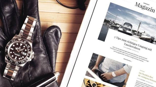 Eine Rolex-Uhr liegt auf einem schwarzen Lederhandschuh neben einem Magazin.