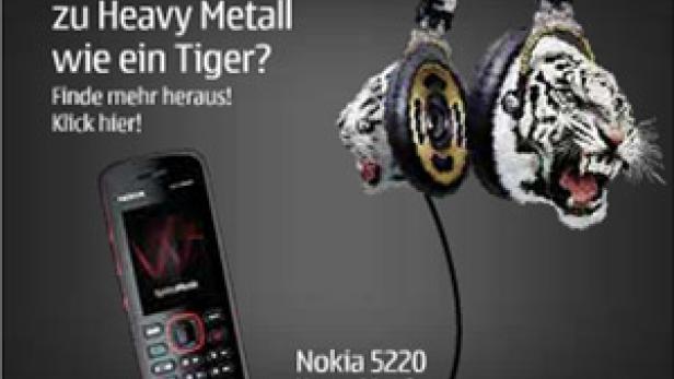 Ein Nokia 5220 XpressMusic Handy neben Kopfhörern mit Tigerfell-Design.