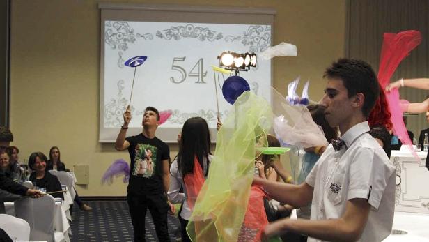 Eine Gruppe von Menschen jongliert mit Tellern und bunten Tüchern auf einer Bühne.