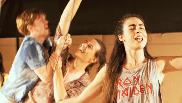 Eine Gruppe junger Schauspieler steht auf einer Bühne und singt.