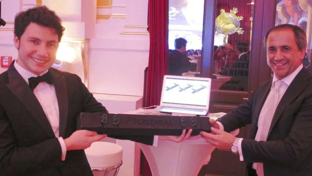 Zwei Männer im Anzug präsentieren einen „Greenrail“-Eisenbahnschwellen-Prototyp.