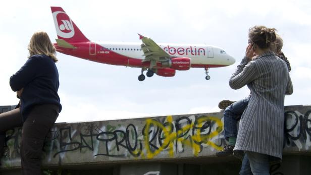 Zwei Frauen und ein Kind beobachten ein landendes Flugzeug von Air Berlin.