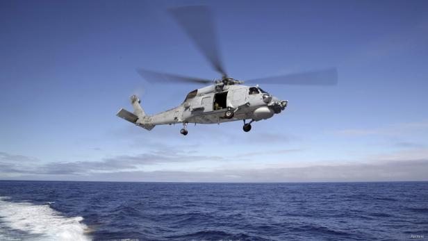 Ein grauer Militärhubschrauber der US Navy fliegt über dem Meer.