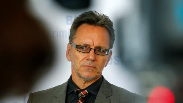 Ein Mann mit Brille, Anzug und Krawatte blickt aufmerksam zur Seite.