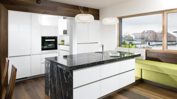 Eine moderne Küche mit einer Kochinsel mit Marmorplatte und weißen Schränken.