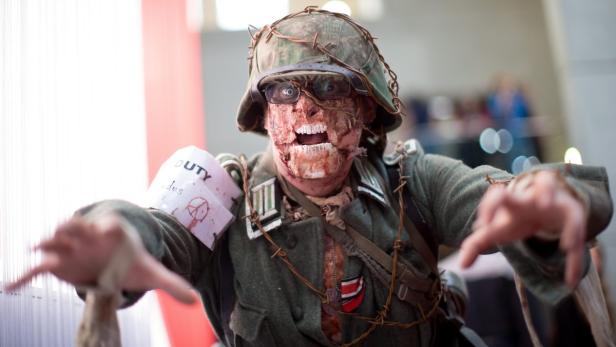 Ein als Zombie verkleideter Mann in einer Militäruniform mit Stacheldraht um den Helm.