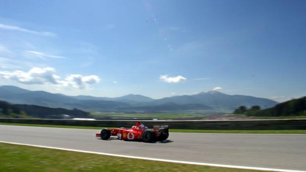 Ein roter Formel-1-Rennwagen fährt auf einer Rennstrecke vor einer Bergkulisse.