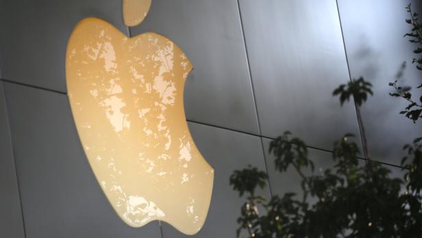 Das Apple-Logo an einem Gebäude, teilweise von einem Baum verdeckt.