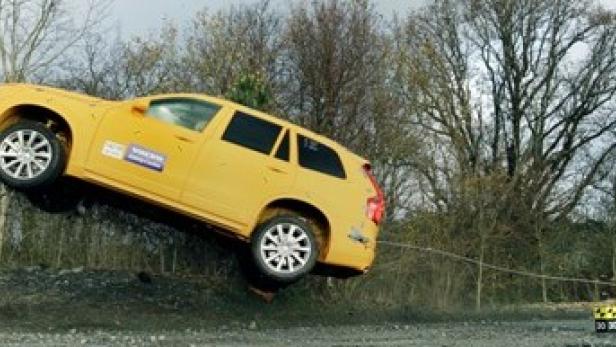 Ein gelber Volvo Kombi bei einem Crashtest, der von einer Rampe abhebt.