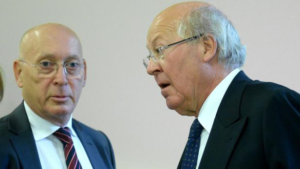 Zwei ältere Männer in Anzügen stehen nebeneinander.