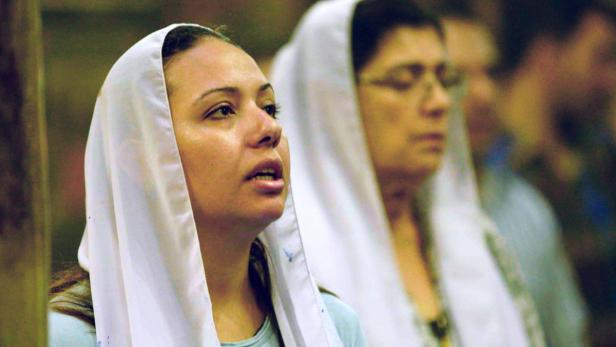 Zwei Frauen mit weißen Kopftüchern beten.