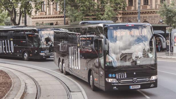 Mehrere schwarze „HELLO“-Busse fahren auf einer Straße mit Straßenbahnschienen.