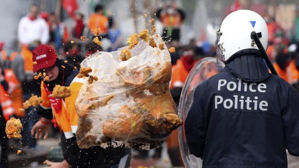 Ein Polizist wird mit einem Sack voller Abfall beworfen.