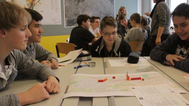 Eine Gruppe von Schülern plant eine Route auf einer Stadtkarte mit Legosteinen.