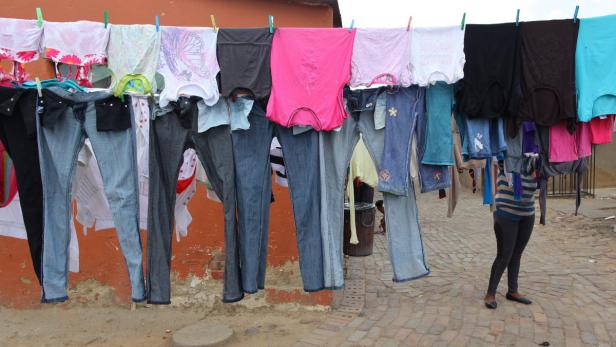 epa03025970 A women stands behind her wet clothes as she hangs them out to dry in the afternoon sun in the Alexandra township, Johannesburg, South Africa, 06 December 2011. EPA/Kim Ludbrook