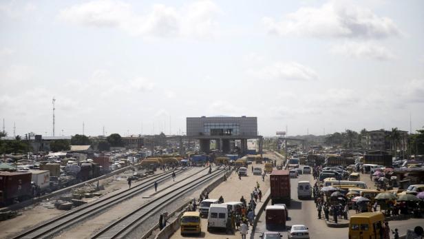 Eine belebte Stadtansicht mit einer Eisenbahnlinie und einem modernen Gebäude im Hintergrund.
