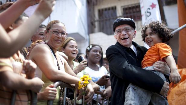 Founder of the National System of Youth and Children&#039;s Orchestras of Venezuela Jose Antonio Abreu carries a child as he arrives at a free concert in the low-income neighborhood of La Vega in Caracas August 2, 2009. As part of the 442th anniversary of the city of Caracas, free classical concerts were organized on the streets by local authorities. REUTERS/Carlos Garcia Rawlins (VENEZUELA SOCIETY)