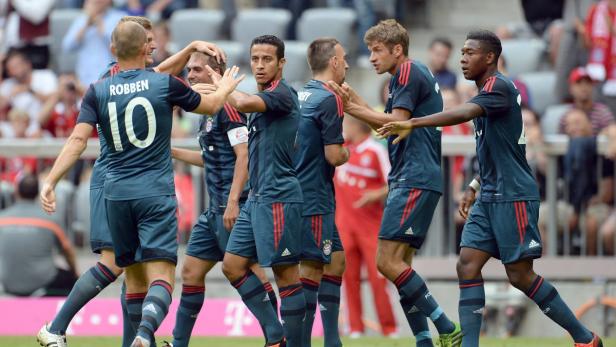 Mehrere Fußballspieler des FC Bayern München feiern gemeinsam auf dem Rasen.